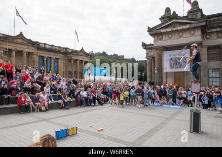 Ein Straßenkünstler unterhält die Menge auf dem Mound in Edinburgh Teil des Edinburgh Festival Fringe, das größte Kunstfestival der Welt. Stockfoto