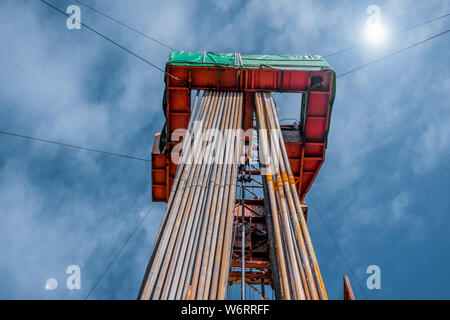 Bohrinsel Derrick im Ölfeld gegen den strahlend blauen Himmel. Bohranlage in Öl Feld für Bohrungen in den Untergrund, um Erdöl produziert. Petroleum I Stockfoto