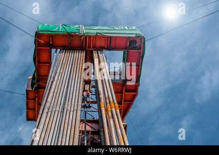 Bohrinsel Derrick im Ölfeld gegen den strahlend blauen Himmel. Bohranlage in Öl Feld für Bohrungen in den Untergrund, um Erdöl produziert. Petroleum I Stockfoto