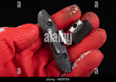 Führen der Gewichte an die Felge am Roten Handschuh. Zubehör für die vulcanizer in der Werkstatt. Der dunkle Hintergrund. Stockfoto