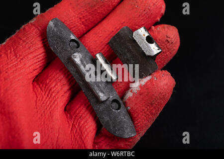 Führen der Gewichte an die Felge am Roten Handschuh. Zubehör für die vulcanizer in der Werkstatt. Der dunkle Hintergrund. Stockfoto