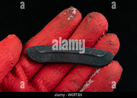 Führen der Gewichte an die Felge am Roten Handschuh. Zubehör für die vulcanizer in der Werkstatt. Der dunkle Hintergrund. Stockfoto