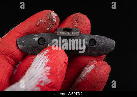 Führen der Gewichte an die Felge am Roten Handschuh. Zubehör für die vulcanizer in der Werkstatt. Der dunkle Hintergrund. Stockfoto