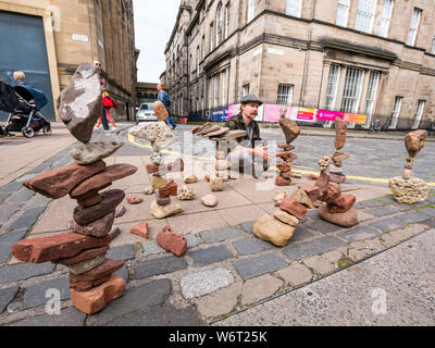 Edinburgh, Schottland, Vereinigtes Königreich, 2. August 2019. Sterling Gregory, ein Stein Balancer aus Amerika, Salden Steine auf einem Gehsteig während des Edinburgh Festival Fringe Stockfoto