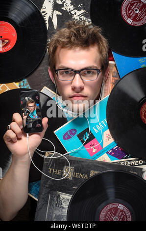 Zwanzig - etwas Kaukasier Männlich unter einer Auswahl von alten Vinyl record Alben begraben, ein Smartphone mit diesem Foto auf der Vorderseite angezeigt. Stockfoto