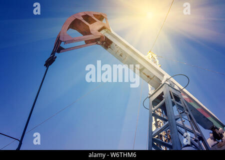 Öl mit Pumpe jack, auf blauen Himmel mit weißen Wolken profiliert, an einem sonnigen Tag im Frühjahr Stockfoto