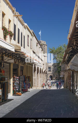 Rhodos, Griechenland: Touristen wandern Sie über eine schmale Straße mit Geschäften in der mittelalterlichen aus dem 14. Jahrhundert befestigte Stadt auf einer Insel der Kykladen in Griechenland. Stockfoto