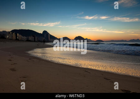 Am frühen Morgen den Strand von Copacabana in Rio de Janeiro mit dem Zuckerhut im Hintergrund kurz vor Sonnenaufgang mit tief orange und blau Stockfoto