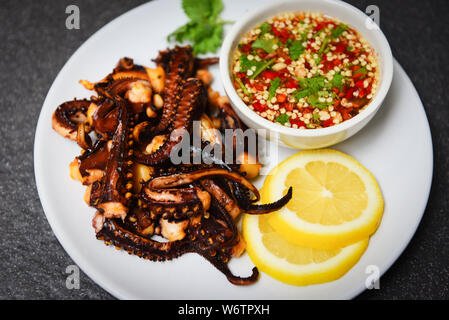 Oktopus Salat mit Zitrone Kräuter und Gewürze auf weiße Platte/Tentakel Tintenfisch gegrillt Vorspeise essen heiß und würzig Chili Sauce gekocht serviert Meeresfrüchte Stockfoto