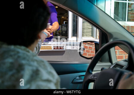 Fast food von Mitarbeitern und Kunden die Hände in einer Transaktion an der Drive Thru. Stockfoto