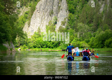 Eine Gruppe von Freunden in einem aufblasbaren Floß auf einem Fluss. Mountain River Wasser Landschaft Stockfoto