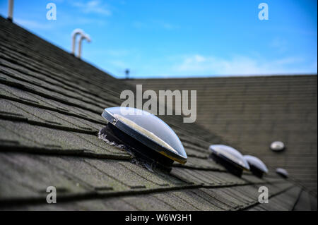 Kuppelförmiges Sonnenröhren-Oberlicht auf Asphalt-Schindeldach Stockfoto