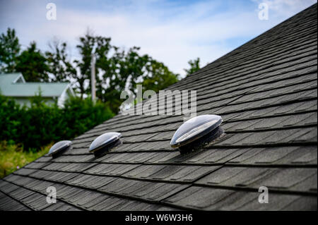 Kuppelförmiges Sonnenröhren-Oberlicht auf Asphalt-Schindeldach Stockfoto