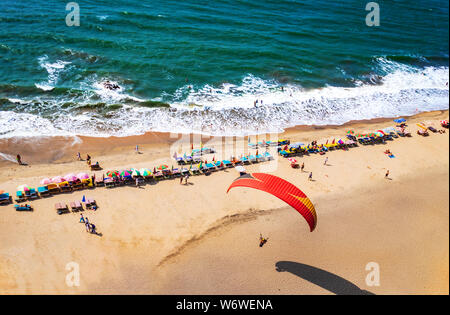 Gleitschirmfliegen in den Himmel. Gleitschirm Tandem über das Meer mit blauem Wasser und Berge im sonnigen Tag fliegen. Luftaufnahme von Gleitschirm und Blau La Stockfoto