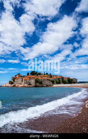 Montenegro, die direkt am Strand liegt, berühmte kleine felsige Insel Sveti Stefan mit alten Häusern aus Stein und roten Dächern im Sommerurlaub Stockfoto