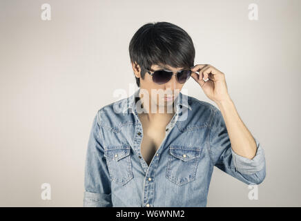 Porträt Mann in Jeans Shirt Mode Brillen zu berühren. Denim Jeans Hemd oder T-Shirt Mode für Männer auf grauem Hintergrund Stockfoto