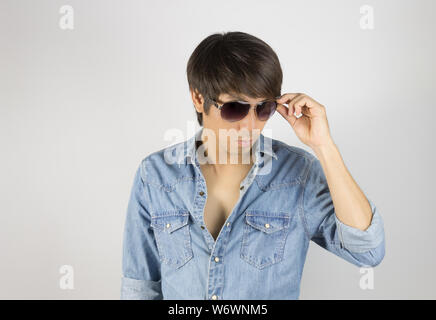 Porträt Mann in Jeans Shirt Mode Brillen zu berühren. Denim Jeans Hemd oder T-Shirt Mode für Männer auf grauem Hintergrund Stockfoto