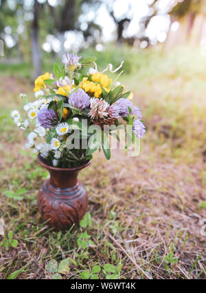 Blumenstrauß aus bunten wilden wilden Blumen in einer zerbrochenen Tontopf auf dem Gras gelegt Stockfoto