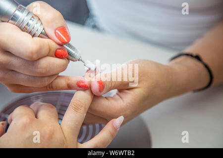 Nahaufnahme von kosmetikerin Hände mit elektrischen Bohrer in Schönheit Maniküre Nail Salon Stockfoto