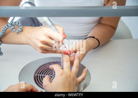 Nahaufnahme von kosmetikerin Hände mit elektrischen Bohrer in Schönheit Maniküre Nail Salon Stockfoto