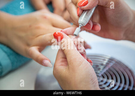 Nahaufnahme von kosmetikerin Hände mit elektrischen Bohrer in Schönheit Maniküre Nail Salon Stockfoto