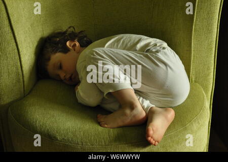 Kind, ein Junge im Schlafanzug, schlafen auf dem Stuhl Stockfoto