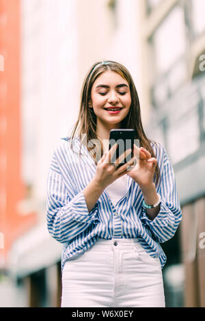 Happy and Frau verwendet ein smart phone auf der Straße Stockfoto