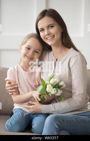 Tochter holding Tulpen mit Mama sitzen auf der Couch zu Hause Stockfoto