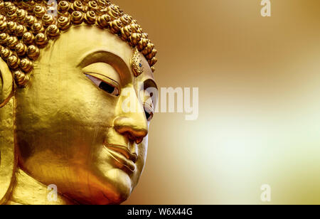 Nahaufnahme Gesicht der Statue Big Buddha in Asien Thailand. golden Bunte auf gelbem Hintergrund verschwimmen Stockfoto