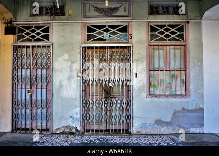 Eingang zu den traditionellen Peranakan shop Haus mit braunen und weißen antiken Tür und Fenster auf verwitterte Wand im historischen Geyland Singapur Stockfoto