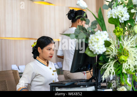 Khaoak, Thailand, 20. Juli 2019: Der Hotel Manager, ein Mädchen, im Gespräch mit den Kunden. Moderner Luxus Hotel in Thailand. Die Rezeption Schreibtisch. Tabelle mit f Stockfoto