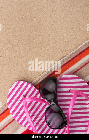 Sommer Zubehör Flip Flops und Handtuch. Sand Strand Textur Hintergrund. Mit Platz für Design, Text platzieren. Stockfoto
