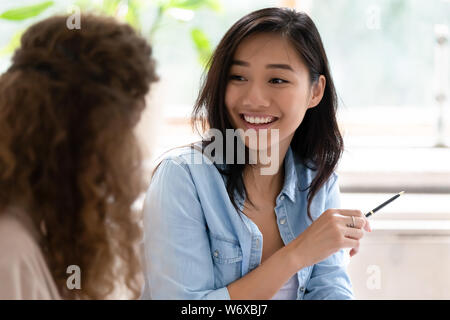 Asiatische Frau im Gespräch mit Kollegen am Schreibtisch zuhause sitzen Stockfoto