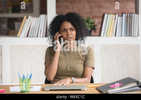 Stirnrunzelnd afrikanischen Geschäftsfrau in unangenehmen Gespräch am Telefon Stockfoto