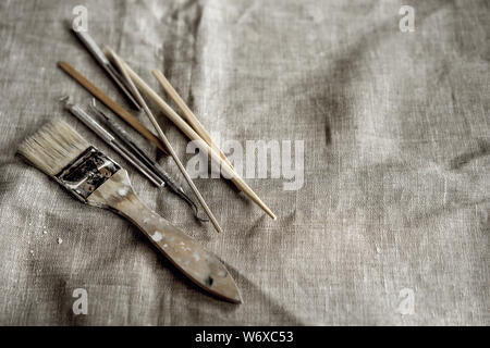 Ton Tools auf graue Leinwand. Pinsel, Holzstäbchen, Stapel, Metall Spatel Stockfoto