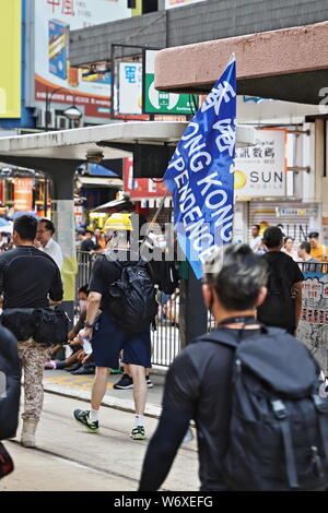 CAUSEWAY BAY, HONG KONG - 25. JULI 2019: Demonstranten ihre Identität mit Sonnenschirmen verbergen, während Sie abschrauben und Fußgänger Barrieren im Voraus entfernen Stockfoto