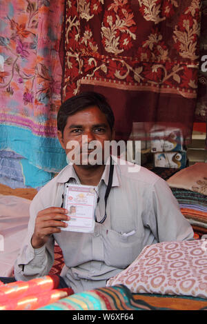 Ladenbesitzer zeigt seinen Ausweis in Kleidung Shop, Surajkund Kunsthandwerk Mela, Surajkund, Faridabad, Haryana, Indien Stockfoto