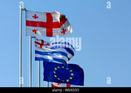 Flagge von Georgia, Adscharien und der Europäischen Union, die im Wind flattern vor blauem Himmel. Stockfoto