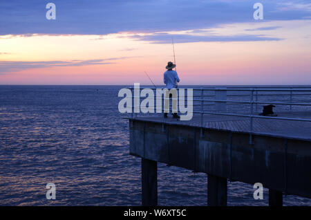 MORGENDLICHER FANG: Ein Mann wird morgens angeln, kurz vor Sonnenaufgang an einem Pier an der Absecon Bucht in der Atlantikstadt, New Jersey. Stockfoto