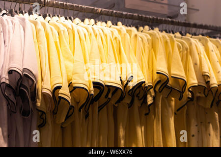 Männer Kleidung, modische, stilvolle auf Kleiderbügeln in den Läden. Das Konzept der Shopping, Verkauf. Gelbe T-Shirts Stockfoto