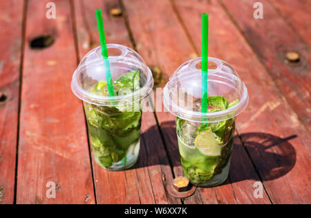 Mojito alkoholfrei, Minze Limonade in Kunststoff Gläser auf einer hölzernen roten Hintergrund, Summer Street Festival Stockfoto