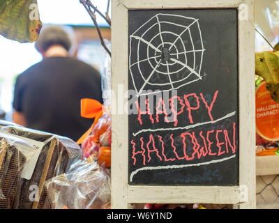 Happy Halloween Spinnennetz anmelden Chalk an Bord geschrieben bei Store mit Kassierer im Hintergrund Stockfoto