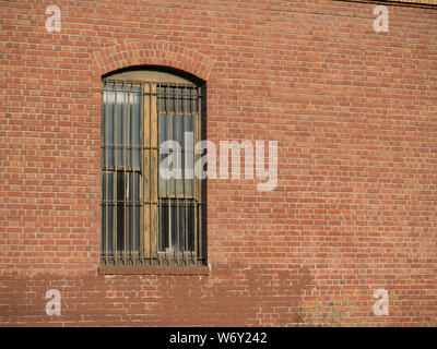 Rusty gated Fenster außerhalb der Brick Warehouse Stockfoto