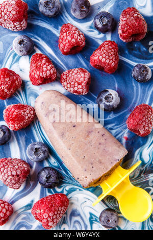 Foto oben gefrorene Heidelbeeren, Himbeeren, Obst Eis auf der blauen Tabelle Stockfoto