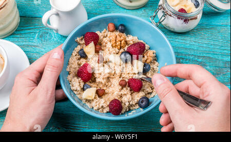 Schüssel Müsli mit Himbeeren und Blaubeeren auf einem blauen Holztisch. Warmes und gesundes Frühstück und Diät essen. Stockfoto