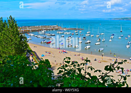 Familien genießen den Sandstrand durch den Hafen von Newquay in W. Wales. einen atemberaubenden Blick über die Cardigan Bay zu Horizont. Sportboote vertäut im Hafen. Stockfoto