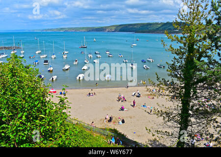 Einen schönen Blick auf die Küste der Cardigan Bay, von Newquay, W. Wales. Familien genießen, Spielen am Strand gesehen, angelegte Boote im Hafen. Stockfoto