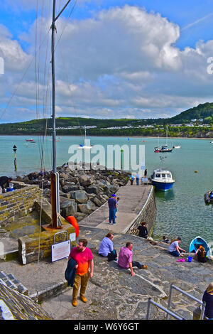 Ein Blick auf die äußeren Mole Hafen von Newquay, W. Wales. Knaben Fischerei auf Krebse. Leute sitzen in der Sonne und Blick über die Bucht. Stockfoto