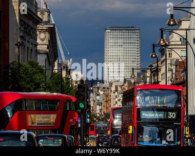 Die Oxford Street London - die Londoner Busse fahren Sie auf der Oxford Street, eine der wichtigsten Einkaufsstraßen von Central London. Mittelpunkt Turm im Hintergrund. Stockfoto