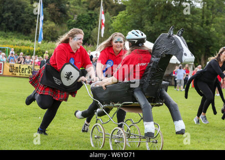 Dundonald, UK. 03. Juli 2019. Die Ayrshire Dorf Dundonald feierte den 30. Jahrestag der Holding Highland Games durch Wettbewerbe von Crazy pram Racing und juvenile Tauziehen neben den traditionellen Wettbewerben der werfen der Caber, wirft den Hammer und die Keppoch Stein heben. Das siegerteam im Kinderwagen race TEAM BRAVEHEART mit Mitgliedern Alex Galloway, REBECCA McNEIL und MORGAN McCORMICK alle von Dundonald. Stockfoto